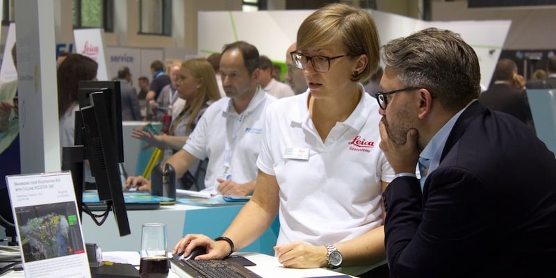 Un equipo de vendedores estudia el software que presentan a los clientes en una feria.