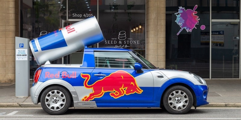Un vehículo es pintado con colores llamativos como parte de la campaña de marketing de una bebida energizante.
