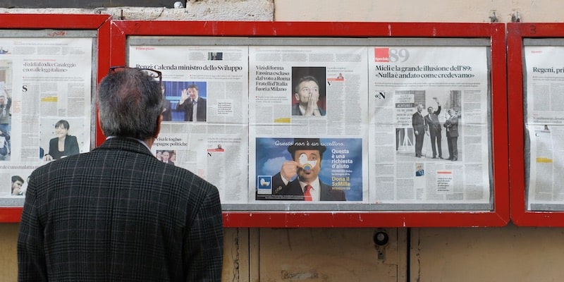 Un hombre lee las noticias que se exhiben en la pared.